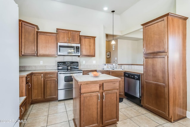 kitchen with a center island, light tile patterned floors, stainless steel appliances, hanging light fixtures, and a sink