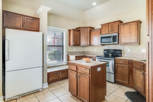 kitchen with tile countertops, appliances with stainless steel finishes, light tile patterned flooring, and a center island