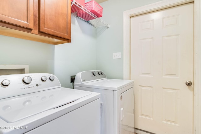 clothes washing area with washing machine and dryer and cabinet space