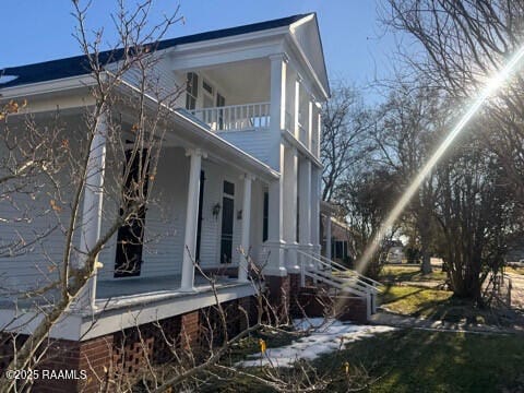 view of side of property featuring a balcony and a porch