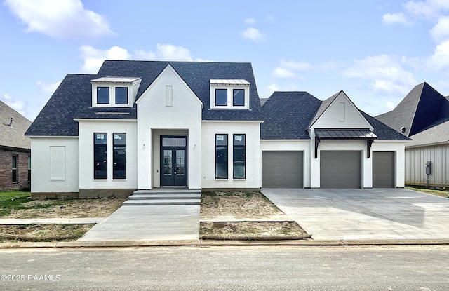 view of front facade featuring french doors, an attached garage, driveway, and roof with shingles