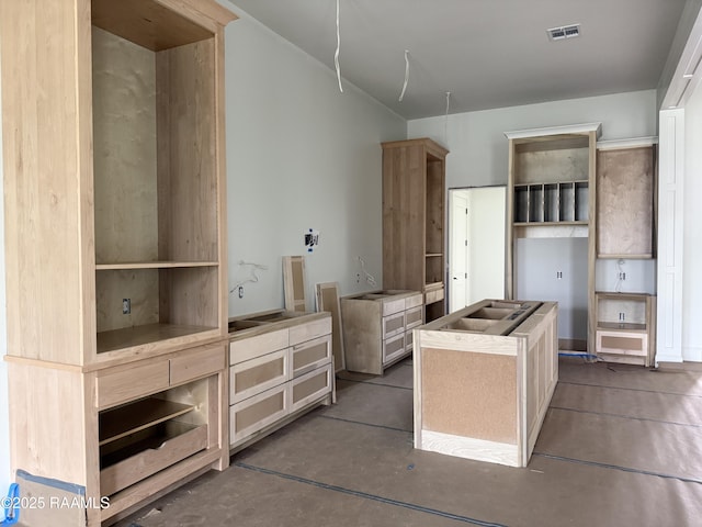 kitchen featuring visible vents, concrete floors, and a kitchen island with sink