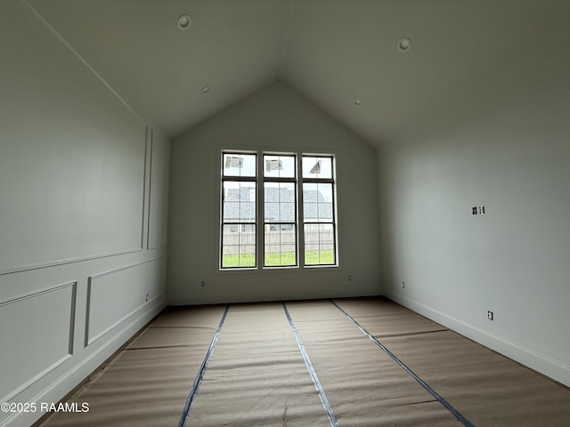 spare room featuring baseboards, lofted ceiling, and wood finished floors