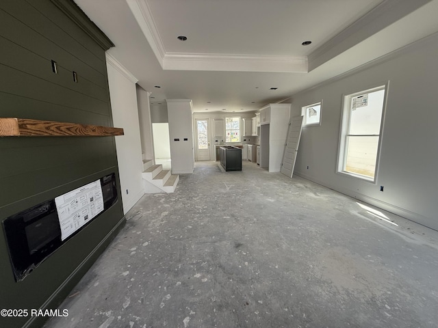 unfurnished living room with stairs, a tray ceiling, and crown molding