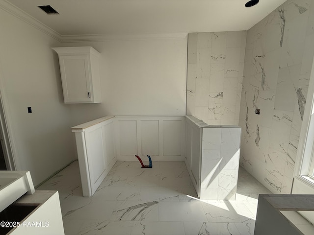 laundry room featuring visible vents, marble finish floor, a decorative wall, wainscoting, and crown molding