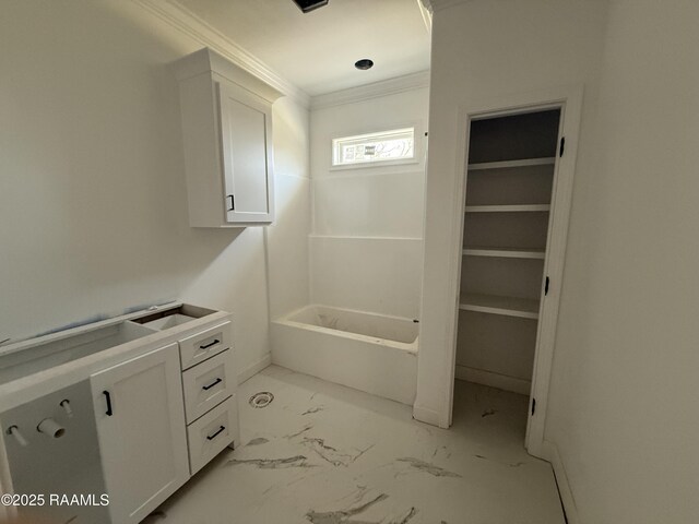 full bath with a bathing tub, marble finish floor, and ornamental molding