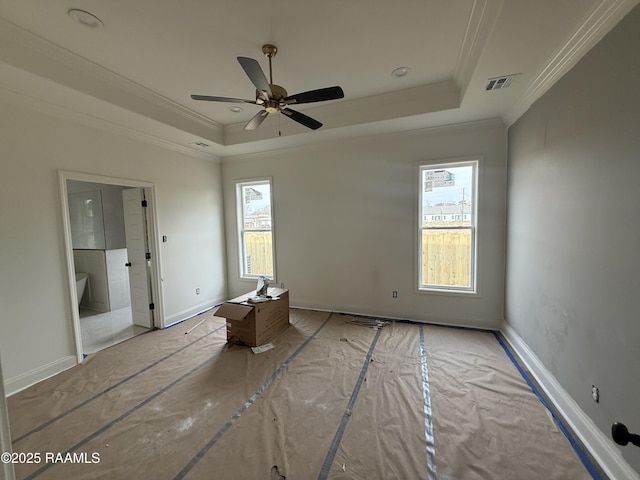 unfurnished bedroom featuring visible vents, a raised ceiling, and multiple windows