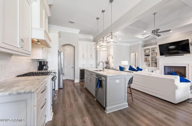 kitchen with arched walkways, stainless steel appliances, visible vents, open floor plan, and premium range hood