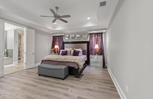 bedroom with baseboards, visible vents, a tray ceiling, crown molding, and light wood-type flooring