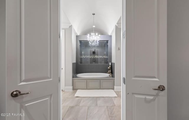 full bath with lofted ceiling, a bath, and a notable chandelier