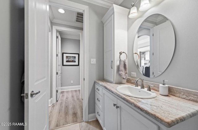 bathroom with visible vents, crown molding, vanity, and baseboards