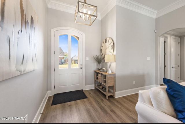 foyer with baseboards, arched walkways, crown molding, and wood finished floors