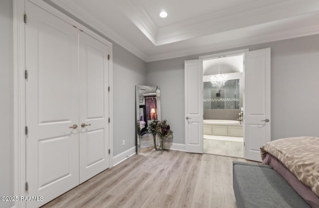 bedroom featuring baseboards, a raised ceiling, light wood-style flooring, an inviting chandelier, and crown molding