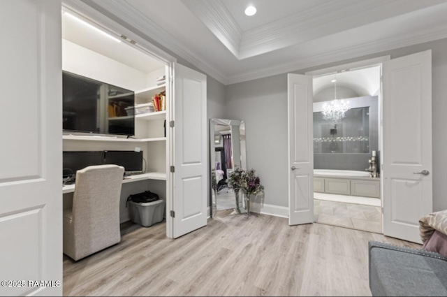 home office featuring light wood-style floors, a notable chandelier, ornamental molding, and built in desk