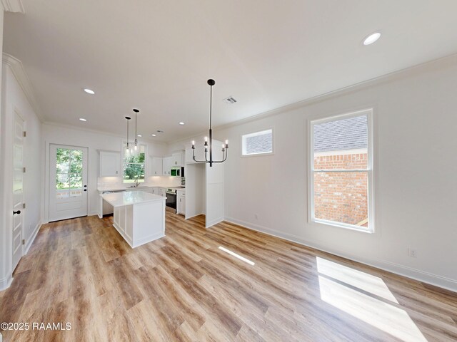 119 Chimney Rock Blvd, Lafayette, LA 70508 - kitchen with ornamental molding, a kitchen island, white cabinetry, light countertops, and light wood-style floors