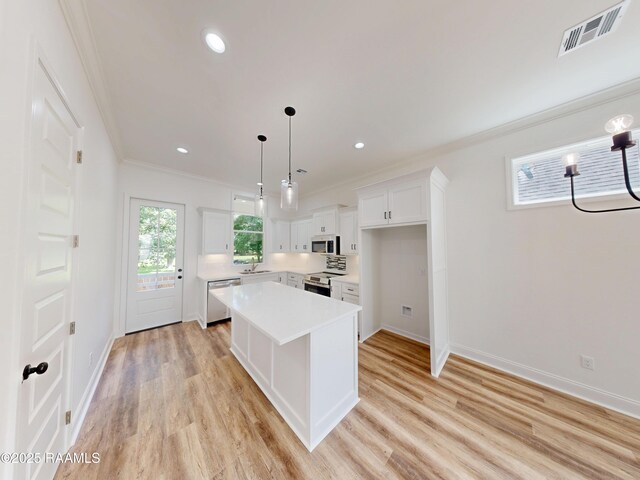 119 Chimney Rock Blvd, Lafayette, LA 70508 - kitchen featuring appliances with stainless steel finishes, crown molding, light countertops, white cabinetry, and a center island