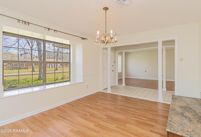 unfurnished dining area featuring a notable chandelier, visible vents, light wood-style flooring, ornamental molding, and baseboards