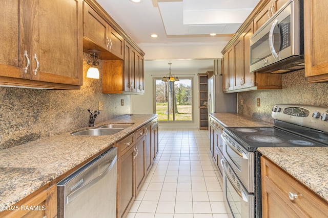 kitchen featuring light tile patterned floors, appliances with stainless steel finishes, brown cabinetry, and a sink