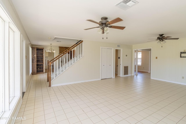 interior space featuring ceiling fan with notable chandelier, visible vents, light tile patterned flooring, and stairs