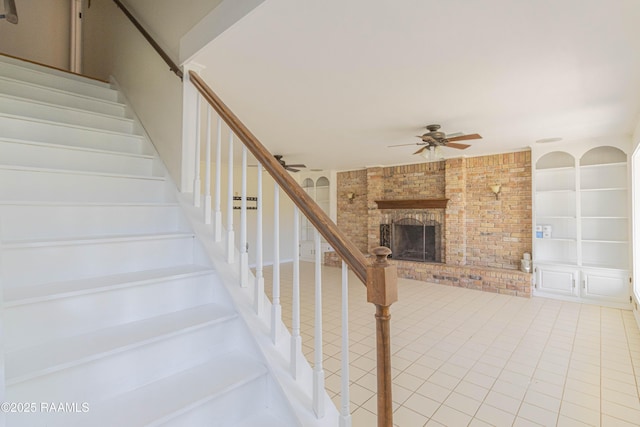 stairway featuring built in features, tile patterned floors, a fireplace, and ceiling fan