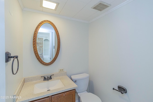 half bathroom with toilet, visible vents, ornamental molding, and vanity