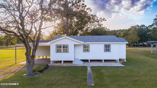 back of house with a yard, a carport, driveway, and a shingled roof