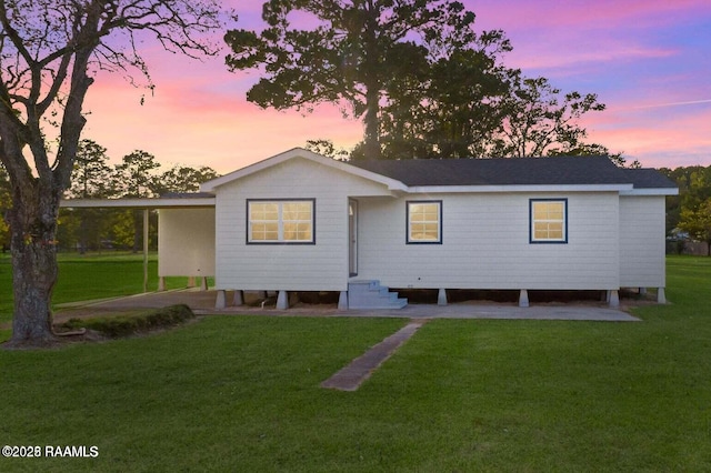 back of property at dusk with a yard, roof with shingles, and entry steps