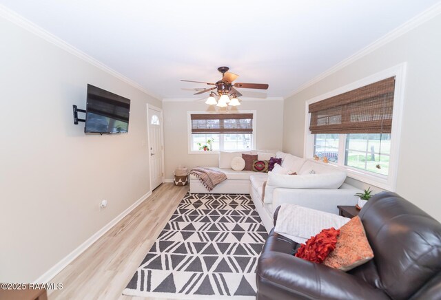 living room featuring crown molding, baseboards, light wood-type flooring, and a wealth of natural light