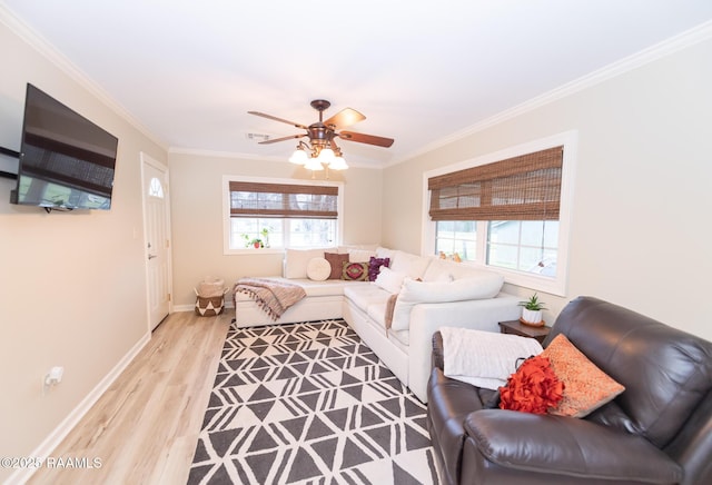 living area with wood finished floors, a ceiling fan, baseboards, and ornamental molding