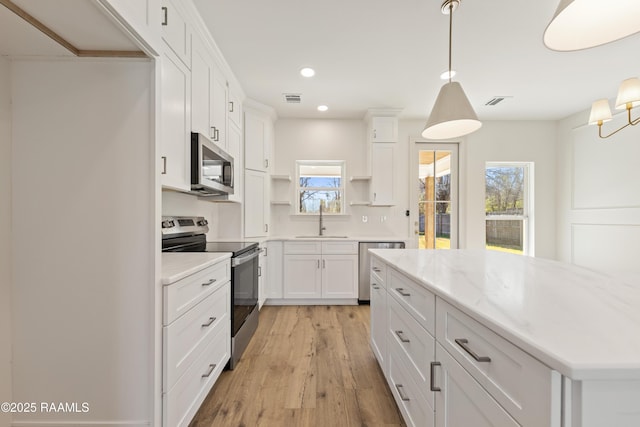 kitchen featuring stainless steel appliances, a sink, visible vents, open shelves, and light wood finished floors