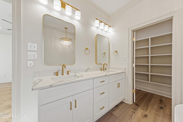 full bathroom with double vanity, ornamental molding, a sink, and wood finished floors