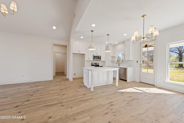 kitchen with a chandelier, stainless steel appliances, a sink, white cabinets, and light countertops