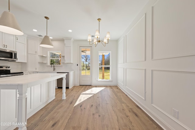 kitchen with a decorative wall, stainless steel appliances, white cabinetry, light countertops, and open shelves