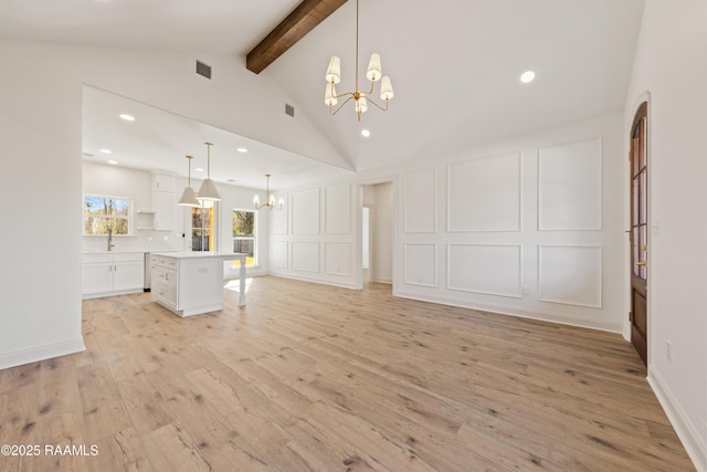 unfurnished living room featuring light wood finished floors, visible vents, a decorative wall, lofted ceiling with beams, and a chandelier