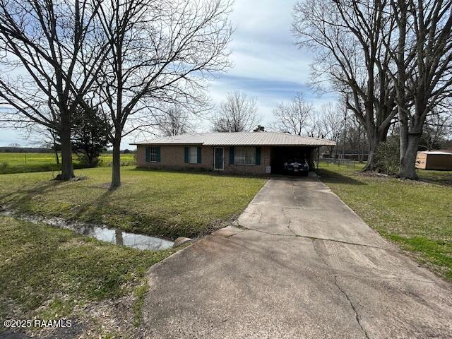 view of front of property featuring concrete driveway, a carport, and a front yard