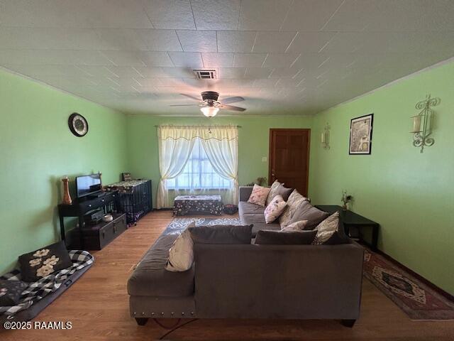 living room with a ceiling fan, visible vents, and wood finished floors