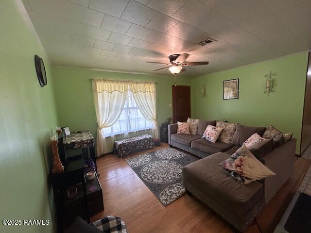 living area with ceiling fan, visible vents, and wood finished floors