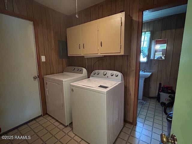 laundry room featuring independent washer and dryer, cabinet space, and wooden walls