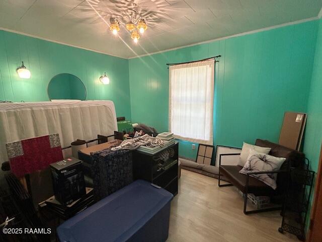 bedroom featuring ornamental molding, an inviting chandelier, and wood finished floors