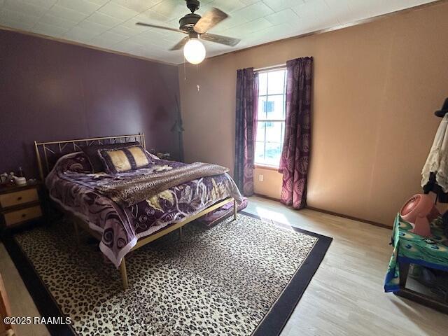 bedroom with ceiling fan, baseboards, and wood finished floors