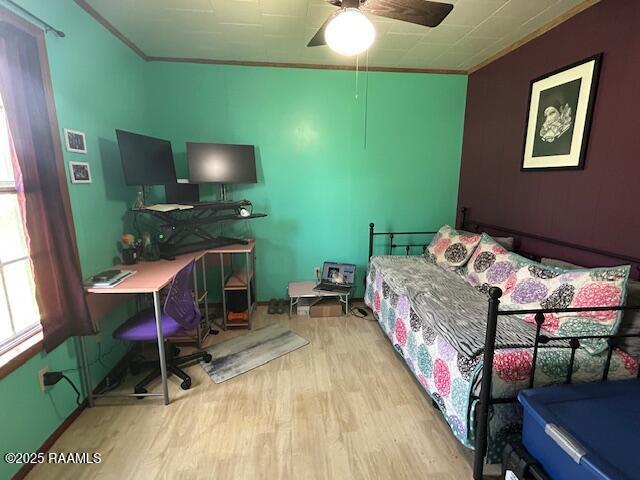 bedroom featuring ornamental molding, wood finished floors, and a ceiling fan