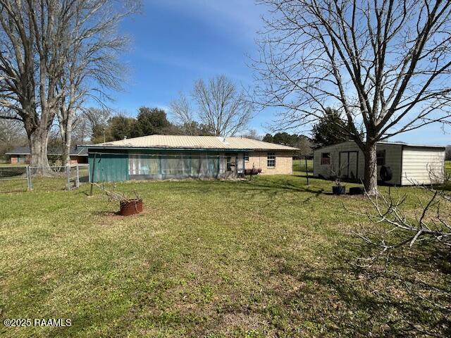 rear view of property with fence, a lawn, and an outdoor structure