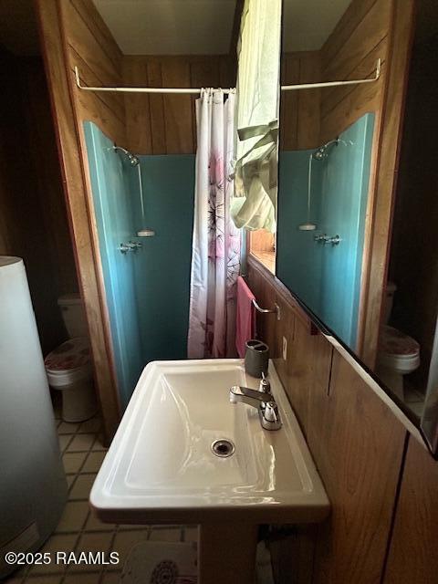 bathroom with toilet, tile patterned flooring, a sink, and a shower with shower curtain