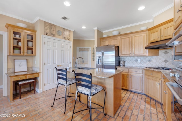 kitchen featuring visible vents, light brown cabinets, a breakfast bar, appliances with stainless steel finishes, and a sink