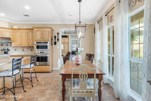 dining area with brick floor, visible vents, an inviting chandelier, and ornamental molding