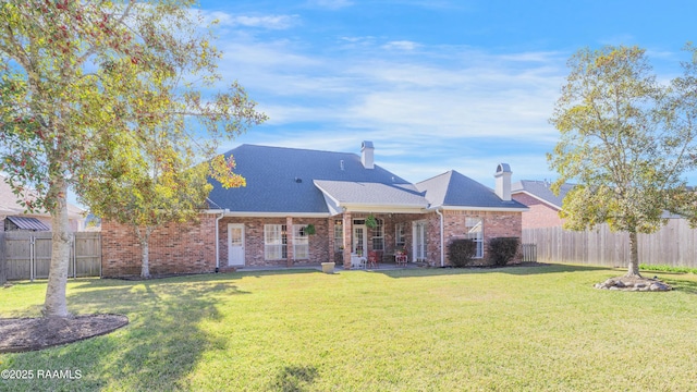 rear view of house featuring a yard, a fenced backyard, and brick siding