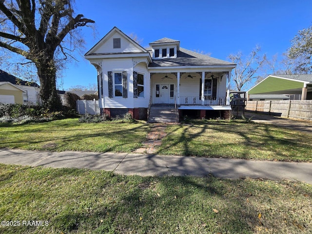 view of front of home featuring fence, a porch, a ceiling fan, and a front yard