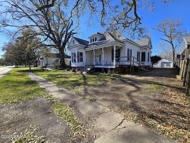 bungalow-style home with covered porch, a front lawn, and fence