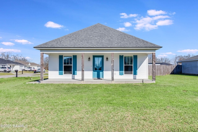 view of front of home with covered porch, a shingled roof, fence, and a front yard