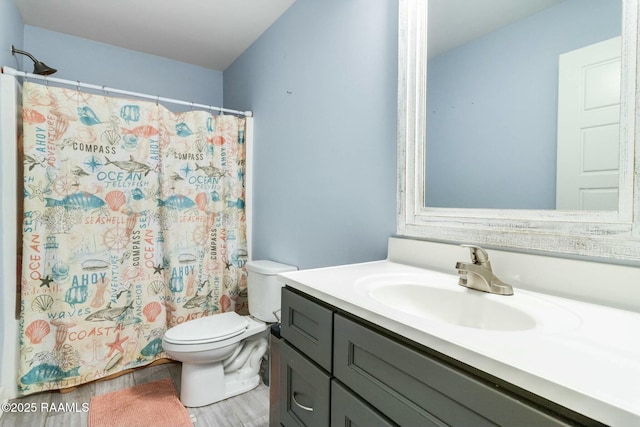 bathroom featuring toilet, a shower with shower curtain, wood finished floors, and vanity